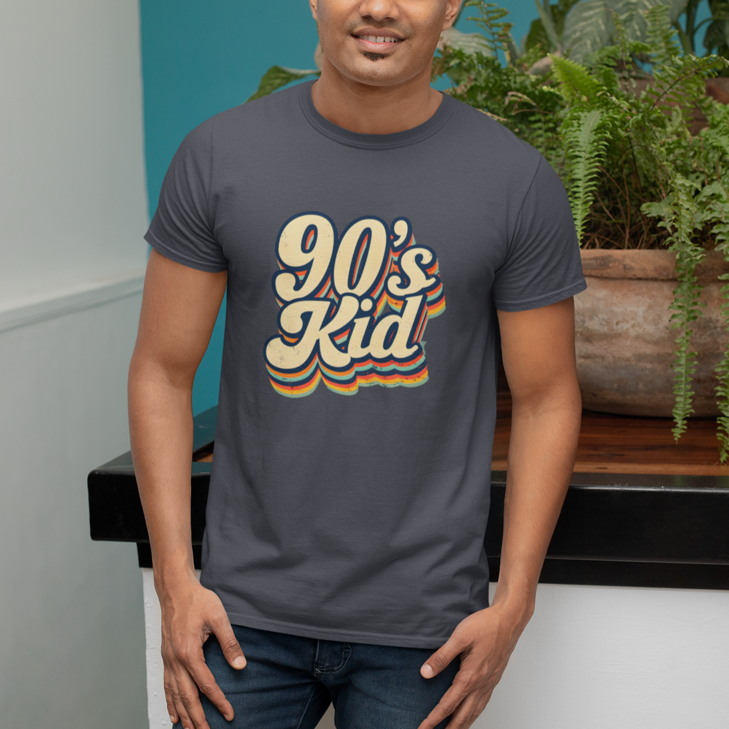 Man wearing a '90s Kid' t-shirt standing in front of a plant