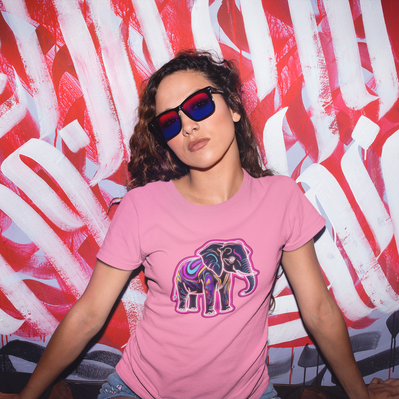 Person wearing a pink t-shirt with an elephant design in front of a colorful abstract background