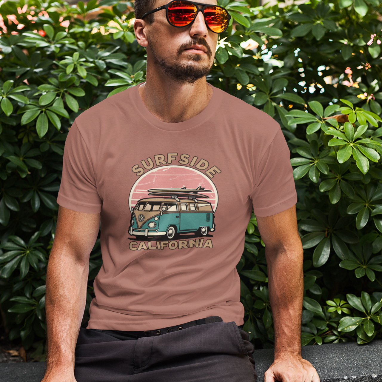 Man wearing a t-shirt with a graphic design of a van and text, sitting outdoors.