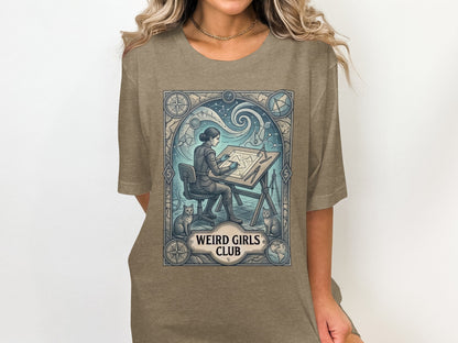 Woman in t-shirt, seated at drafting table with cats, "Weird Girls Club" text.