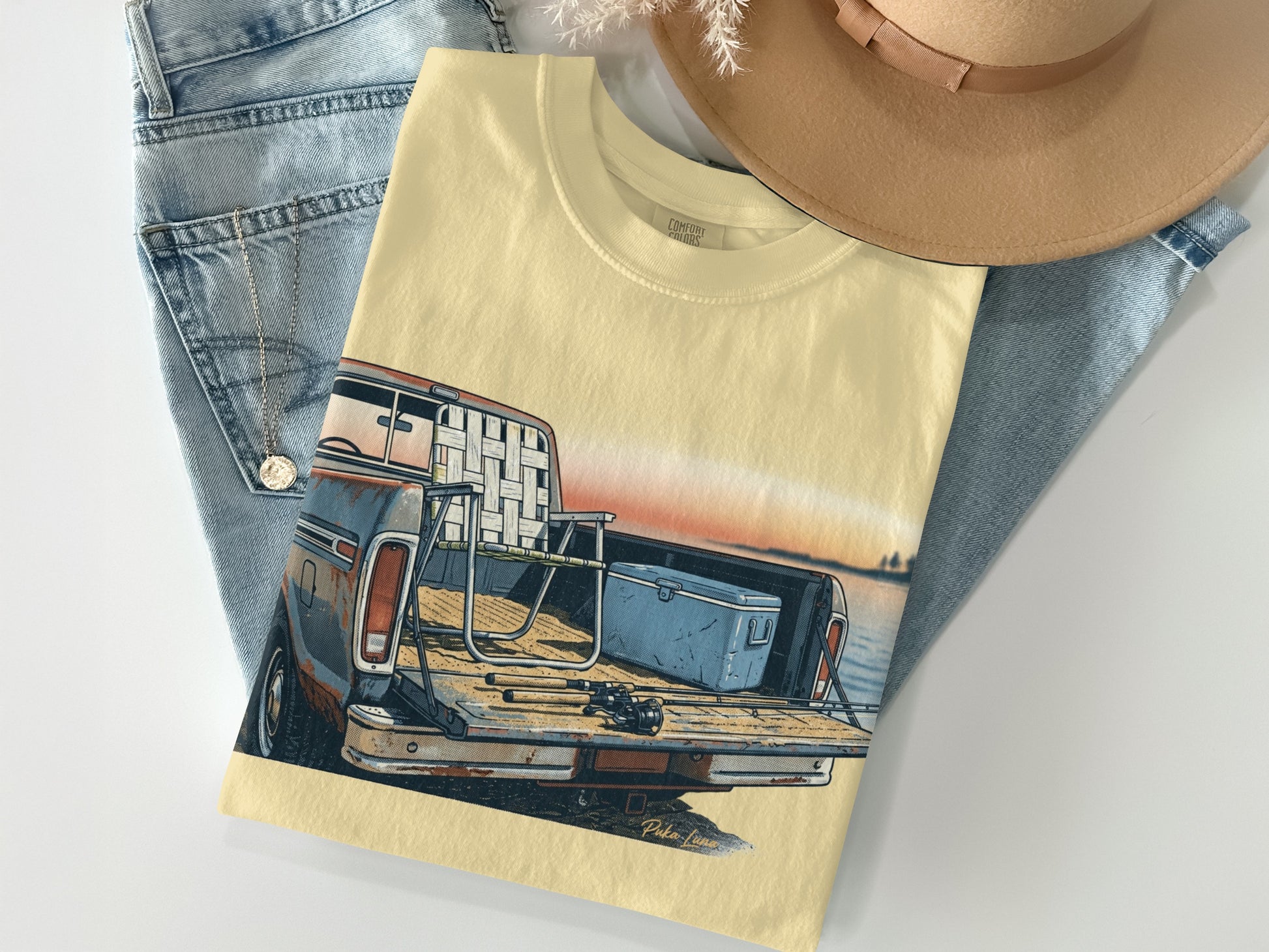 Cream t-shirt with vintage pickup truck graphic and fishing gear in bed.