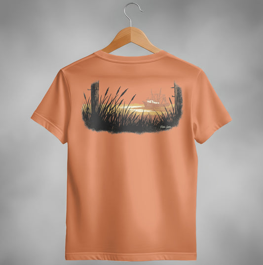 Orange t-shirt with a painting of a boat at sunset behind tall grass.