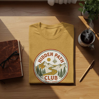 Rugged Hidden Path Club Explorer Wilderness Shirt: Yellow t-shirt with circular "Hidden Path Club" logo, featuring mountains and a winding road.