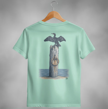 Cormorant perched on a wooden post with a ring, on a beach.