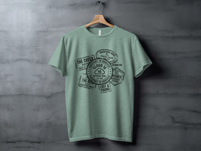 Rugged Wanderlust Passport Stamp Graphic Wilderness Shirt: Green t-shirt with passport stamp-style graphics.