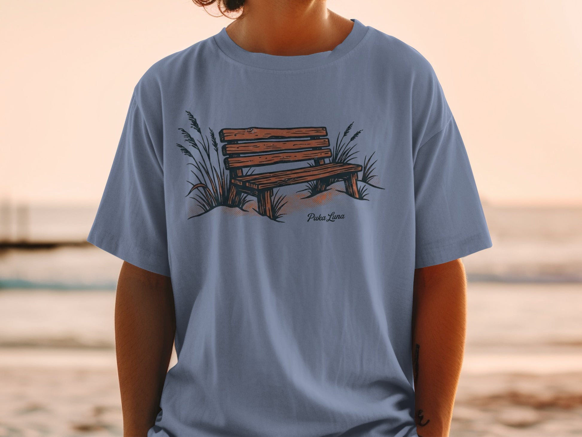 T-shirt with illustration of a wooden park bench and beach grass.