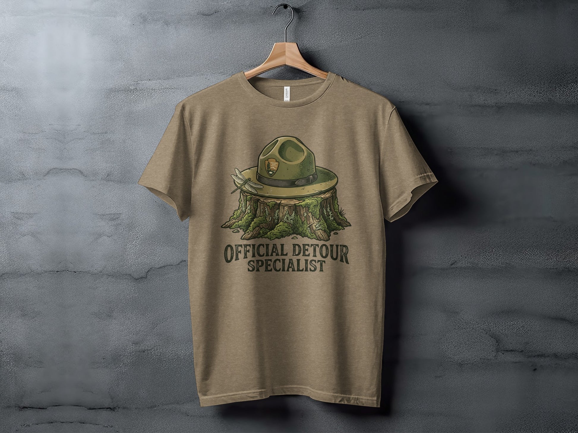 Official Detour Specialist Heritage | Vintage Outdoor Apparel: Tan t-shirt with a park ranger hat on a tree stump, "Official Detour Specialist" text.