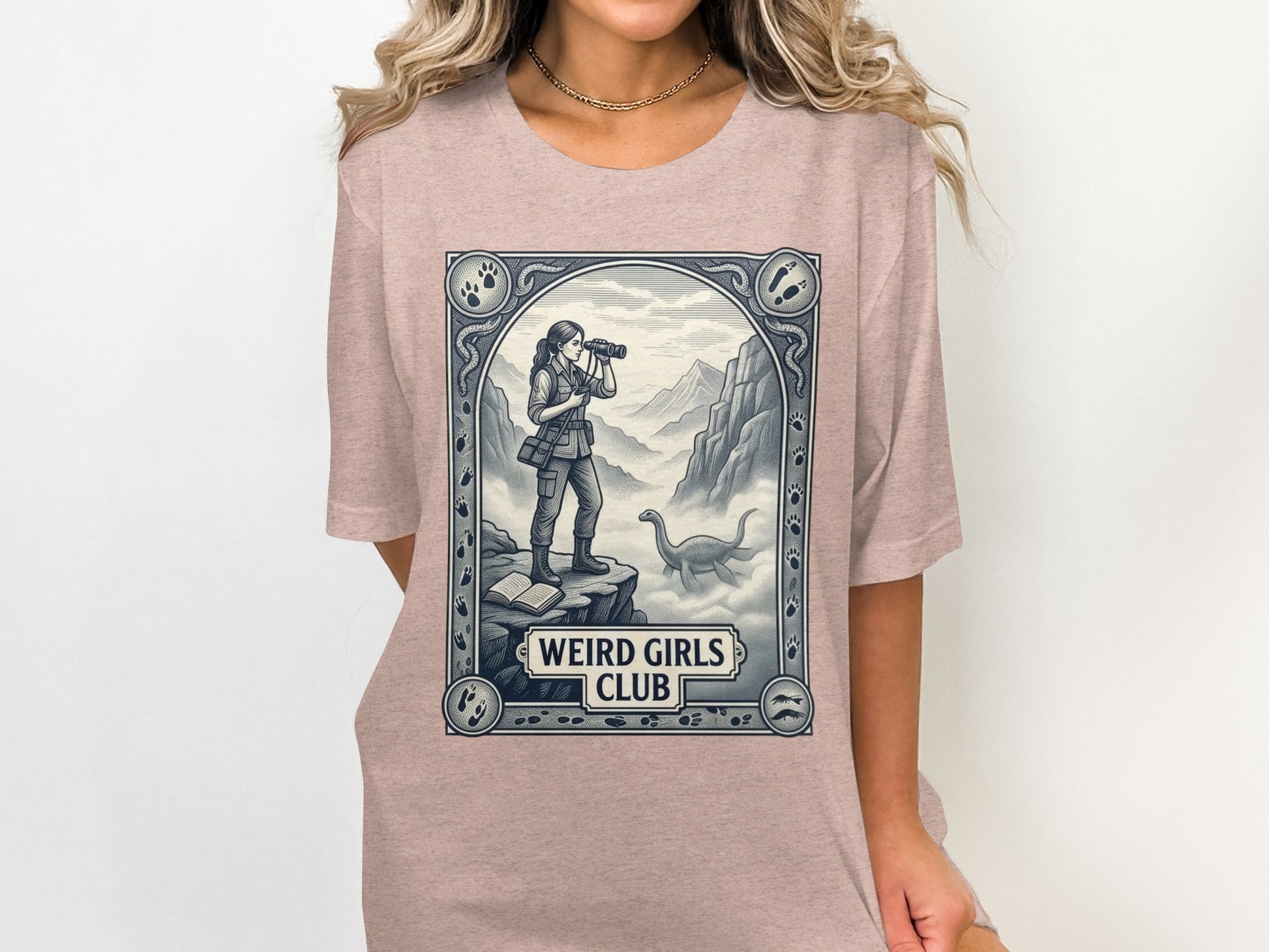Woman in t-shirt with dinosaur and explorer graphic, "Weird Girls Club."