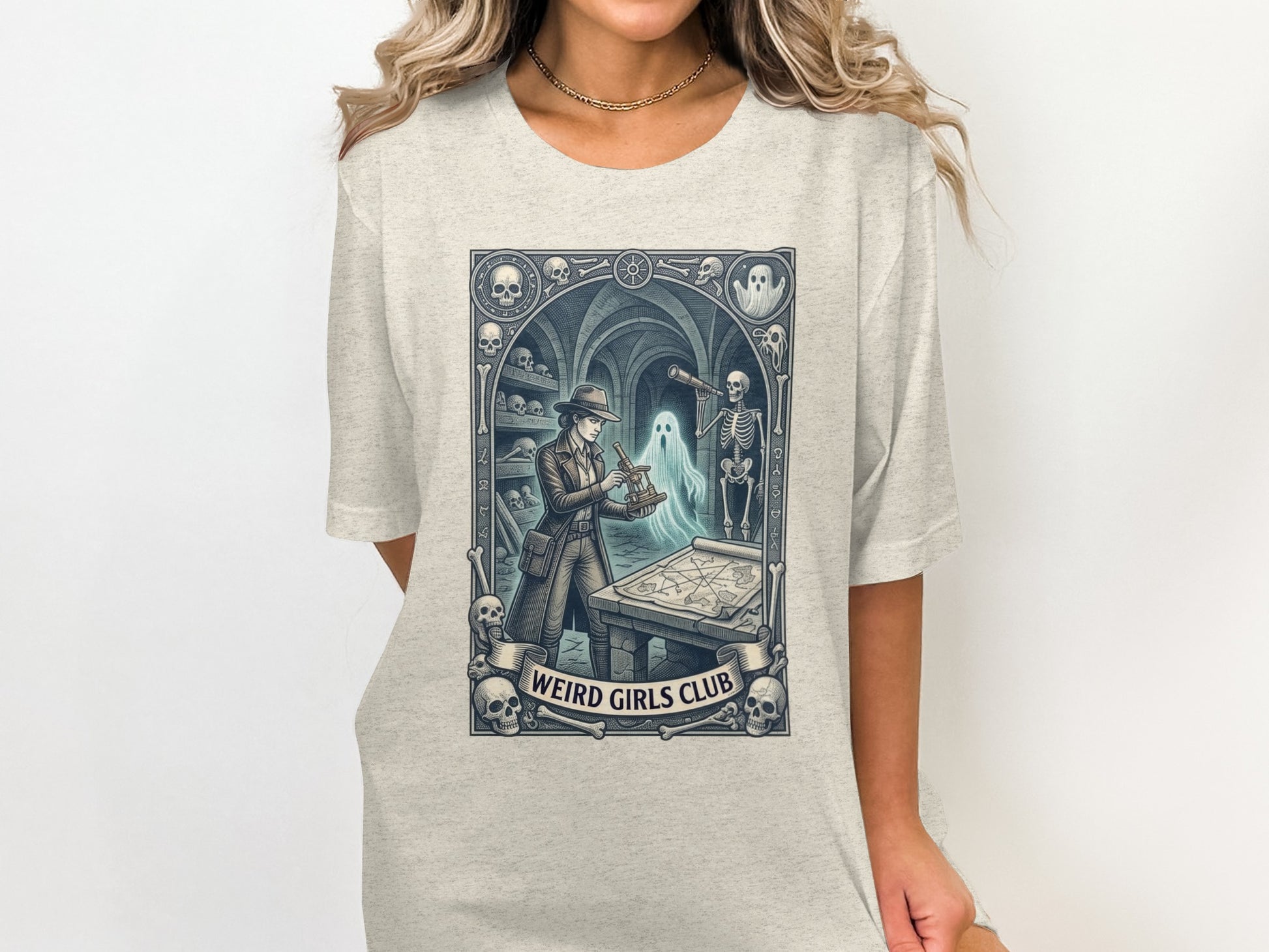 "Weird Girls Club" graphic tee featuring a woman with a skeleton and map in a gothic setting.