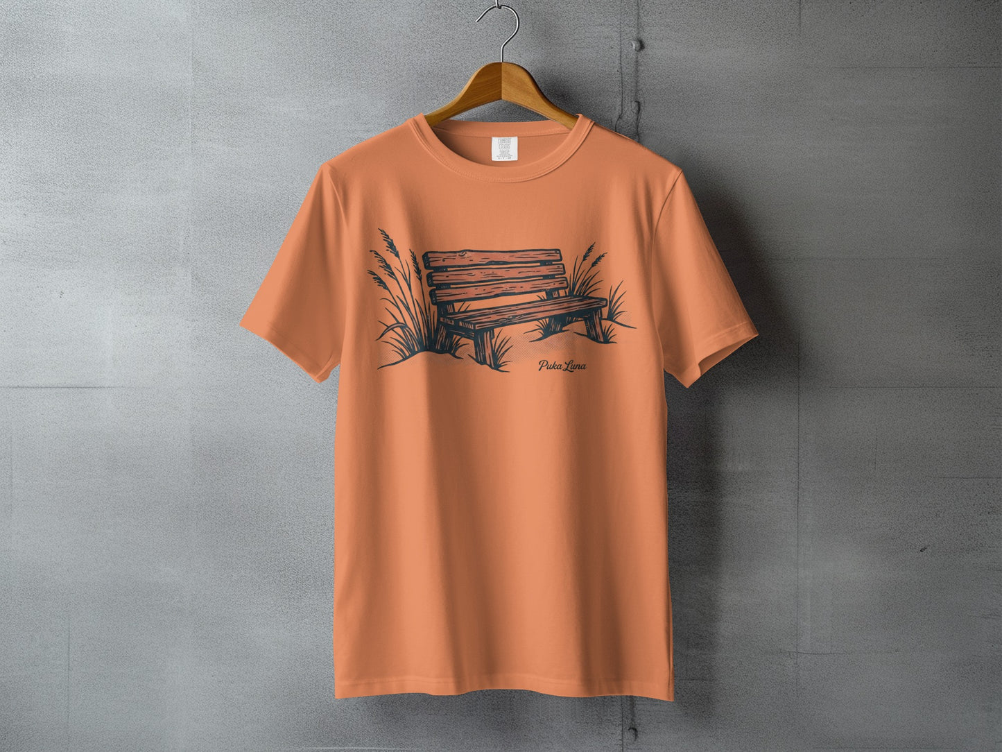 Orange t-shirt with a sketch of a park bench and grass.