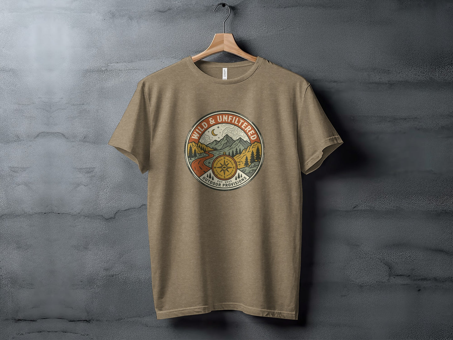 Rugged Wild & Unfiltered Explorer Wilderness Shirt: Tan t-shirt featuring a circular logo with mountains, a road, and "Wild & Unfiltered Outdoor Provisions."