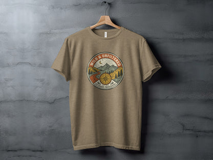 Rugged Wild & Unfiltered Explorer Wilderness Shirt: Tan t-shirt featuring a circular logo with mountains, a road, and "Wild & Unfiltered Outdoor Provisions."