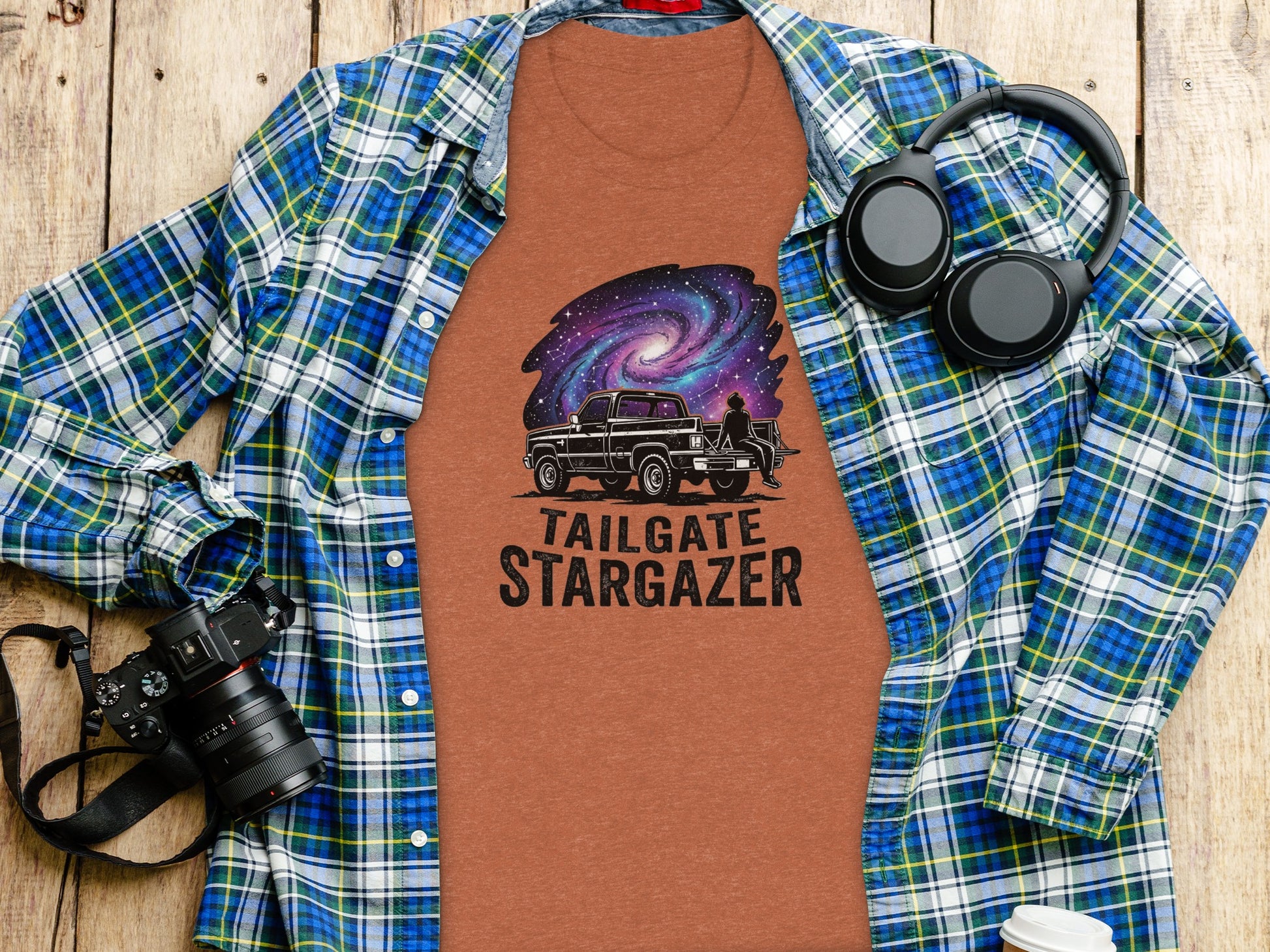 Heritage Cosmic Tailgate Stargazer Nomad Tee: T-shirt with galaxy and truck graphic, laid on a plaid shirt and wooden surface.