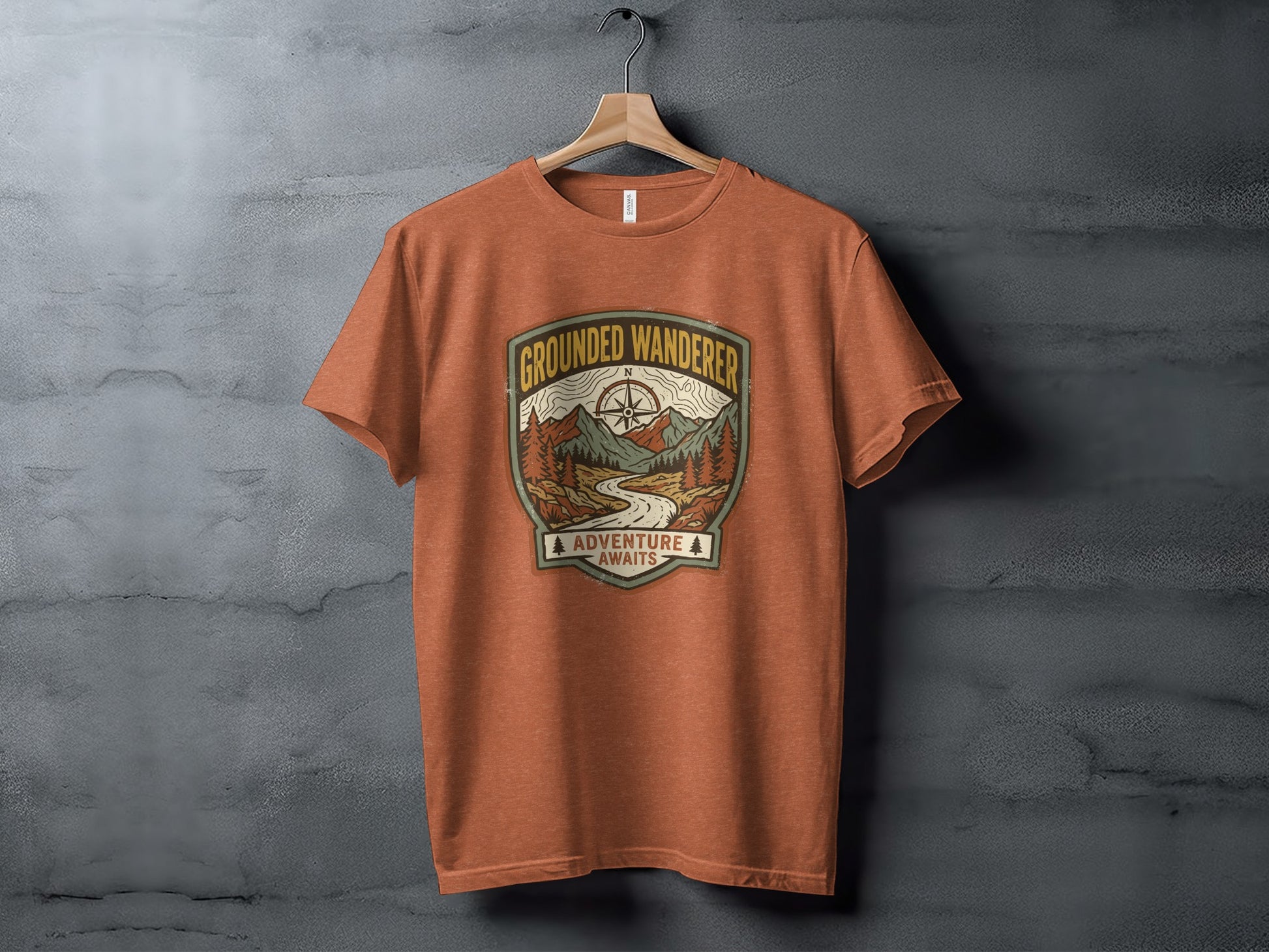 Heritage Grounded Wanderer Adventure Nomad Tee: Orange t-shirt with "Grounded Wanderer Adventure Awaits" graphic featuring mountains and a path.