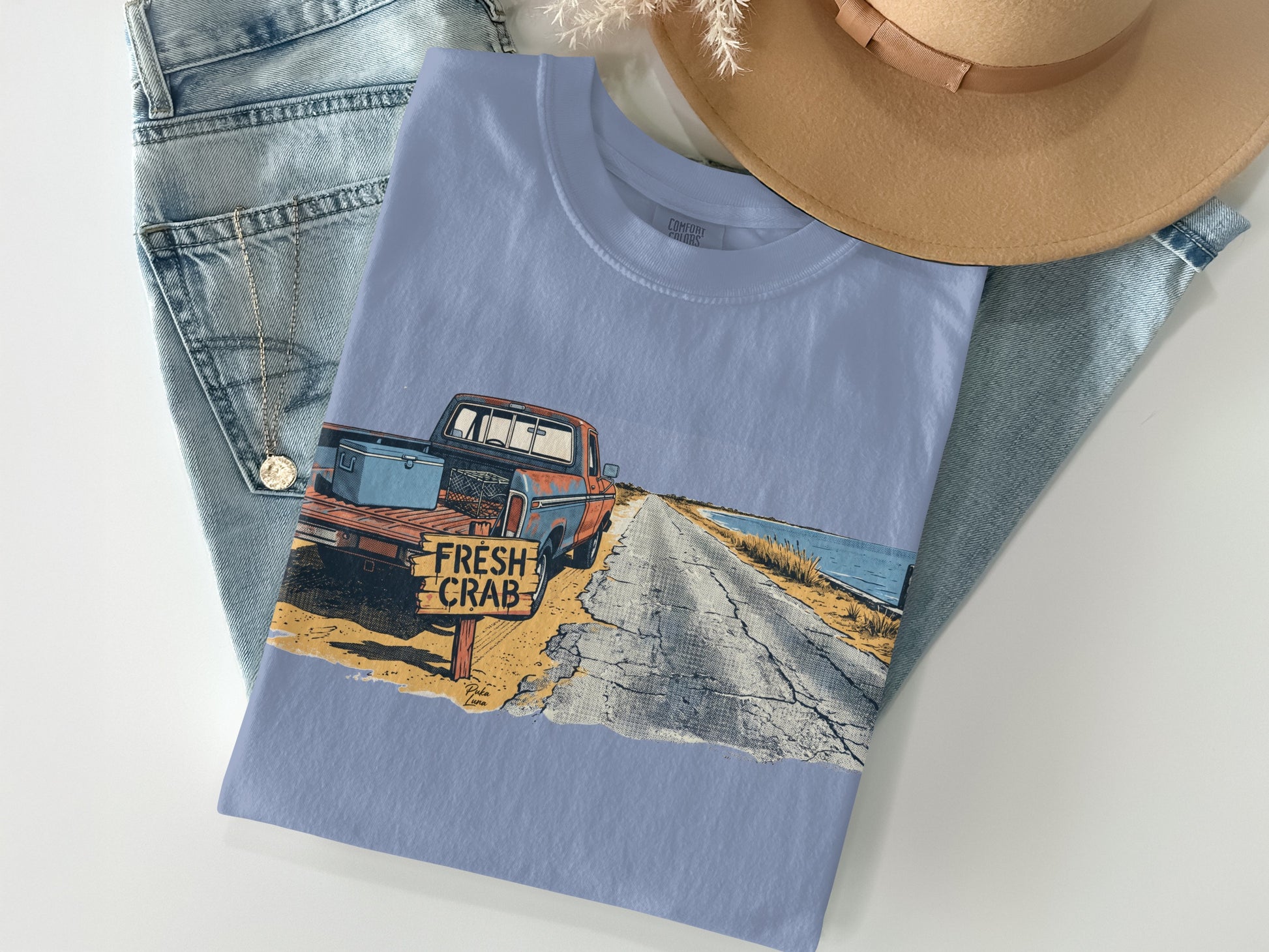 Light blue t-shirt with graphic of a vintage truck on a coastal road.