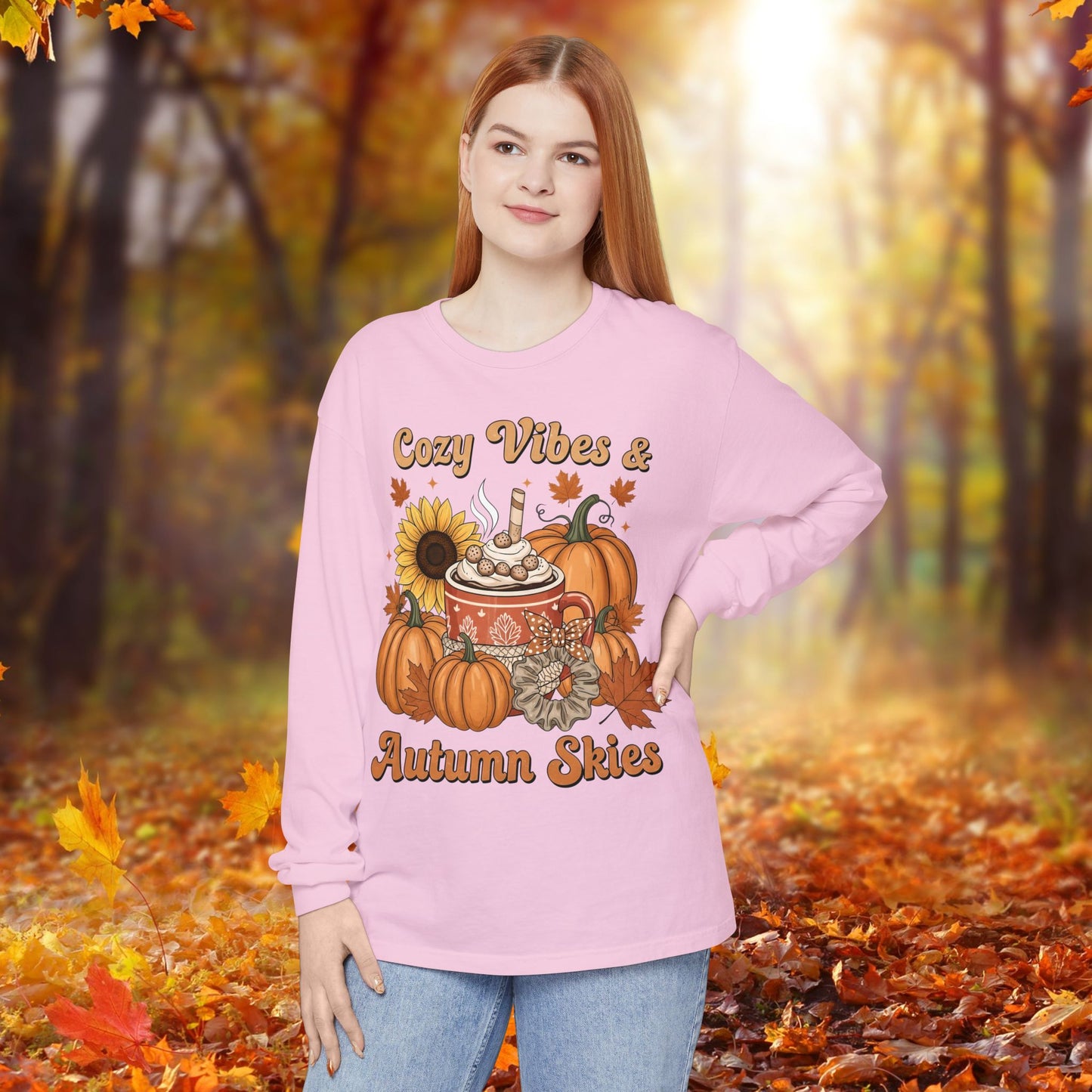 Person wearing a pink sweatshirt with autumn-themed design in an autumn forest setting