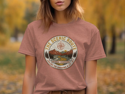 Heritage Scenic Route Vintage Explorer Tee Nomad Tee: Rose-colored t-shirt featuring "The Scenic Route Outdoor Excursions" circular logo with mountains and trees.