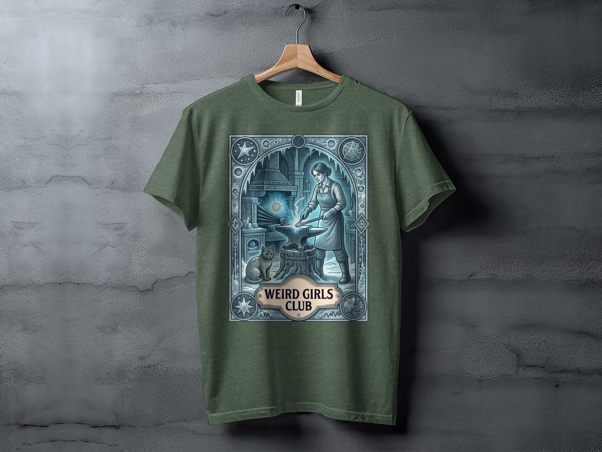 Green t-shirt featuring an anvil, blacksmith, cat, and "Weird Girls Club" text.