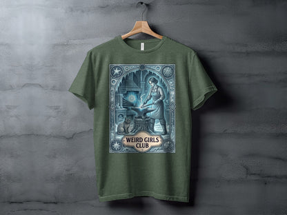 Green t-shirt featuring an anvil, blacksmith, cat, and "Weird Girls Club" text.