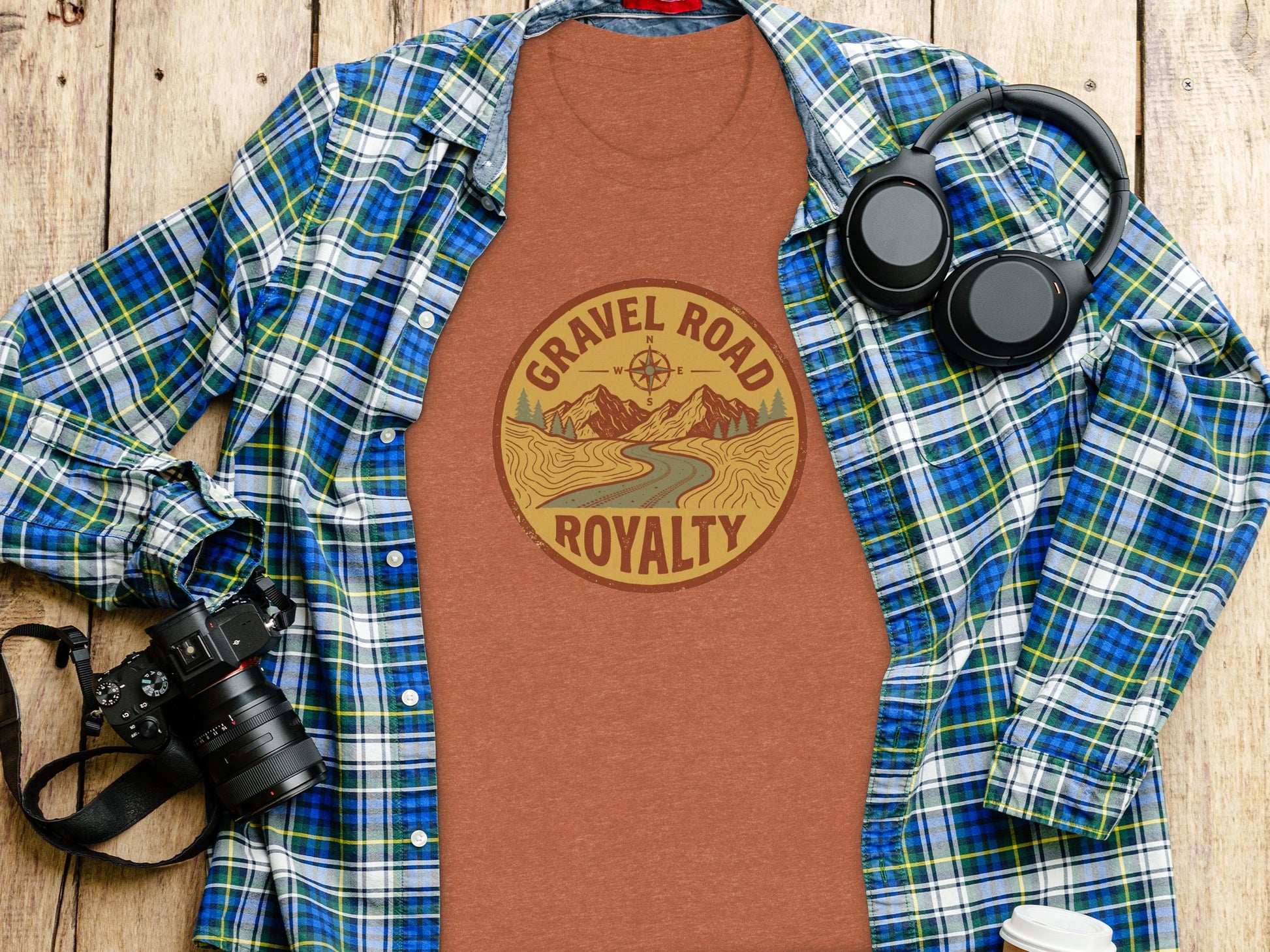 Gravel Road Royalty Adventure Tee | Vintage Outdoor Apparel: Flannel shirt, headphones, and camera laid out with a graphic tee reading "Gravel Road Royalty".
