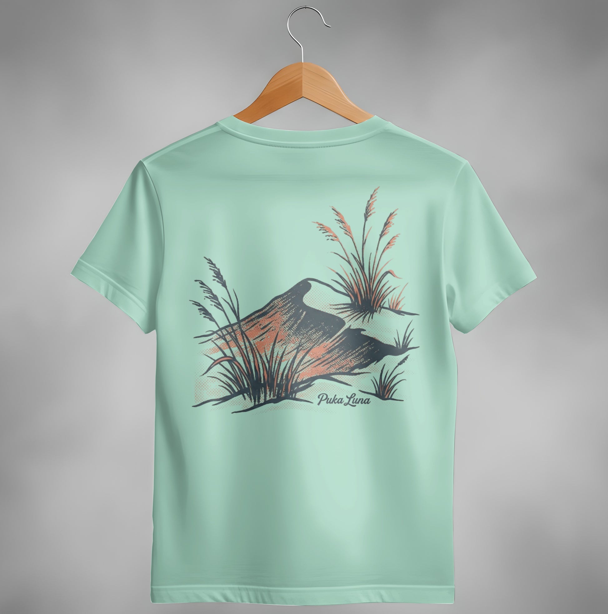 Mint green t-shirt with abstract mountain and grass design and "Puka Luna" text.