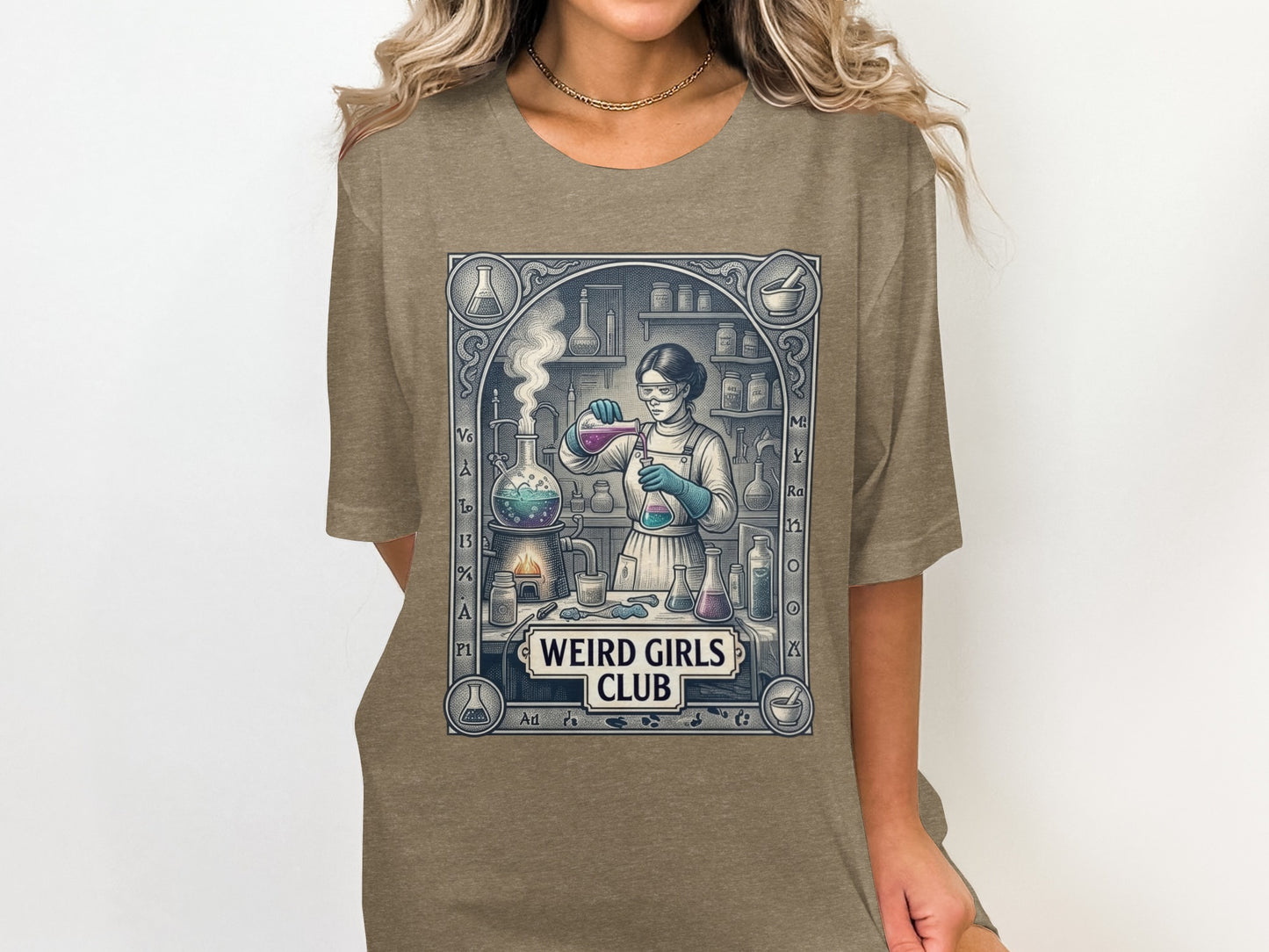 Graphic tee with a woman in a lab coat pouring liquid into beakers, "Weird Girls Club" text.