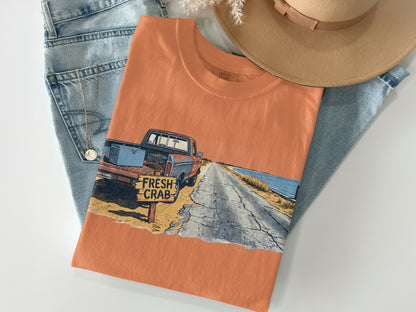 Orange t-shirt with a graphic of a vintage truck and "Fresh Crab" sign.