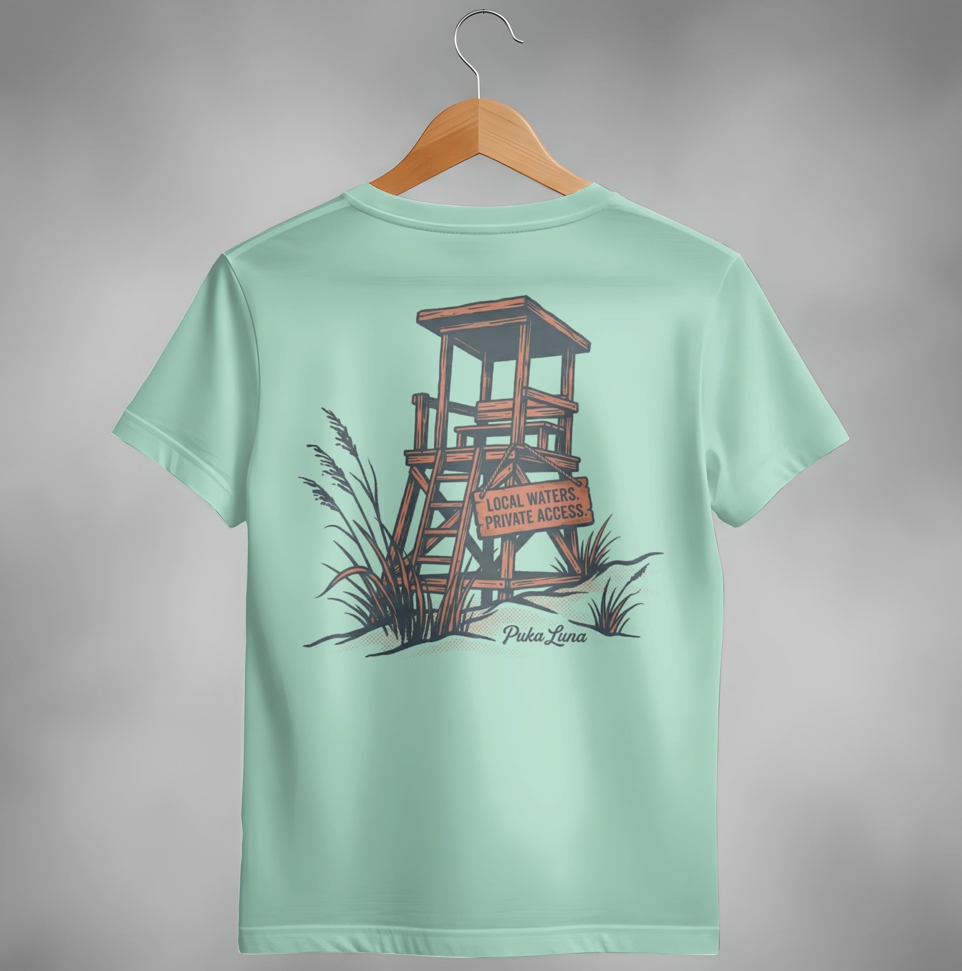 Pale teal t-shirt featuring a wooden lifeguard stand and "Puka Luna" text.