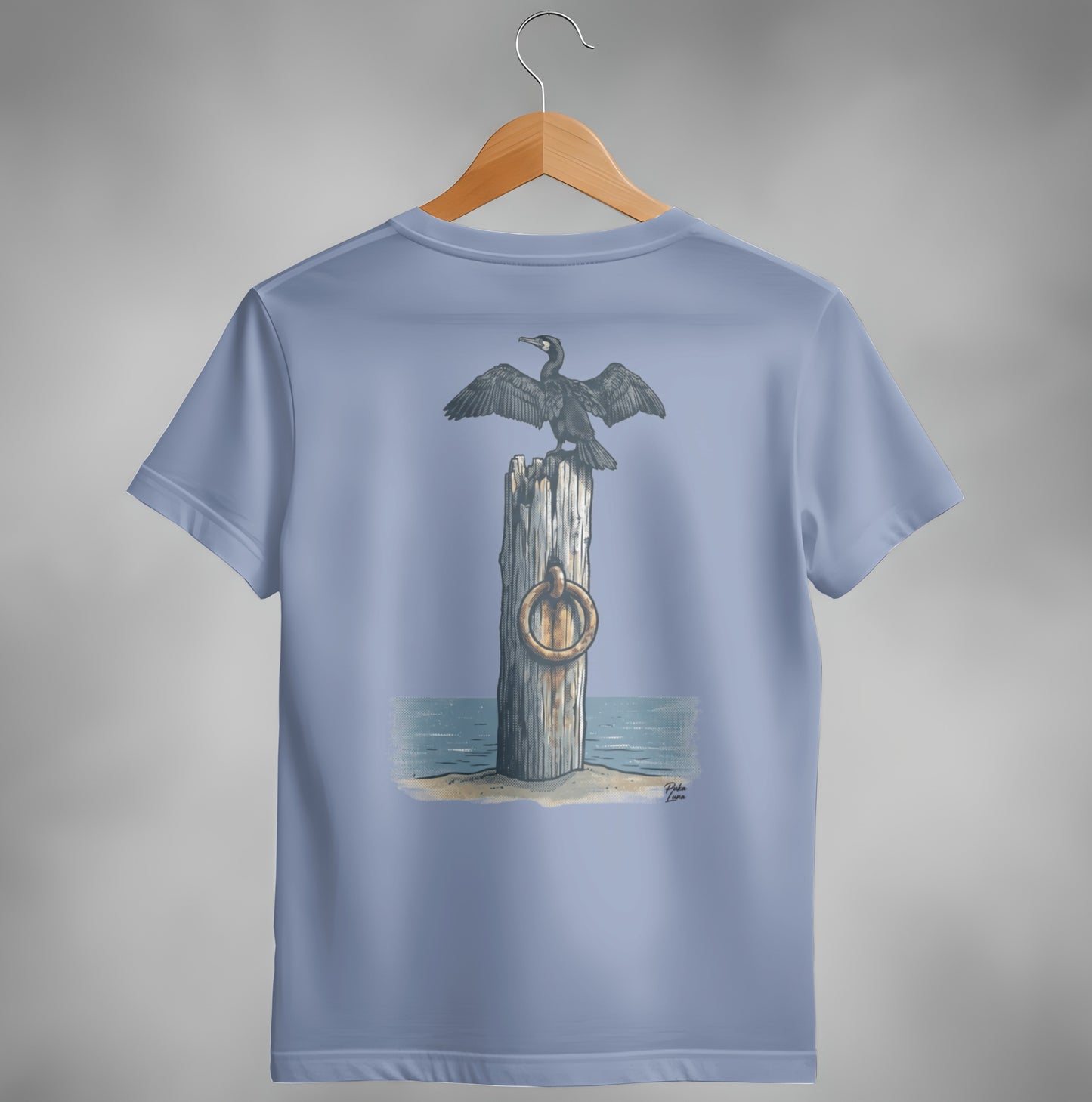 T-shirt with illustration of a cormorant perched on a weathered post by the sea.