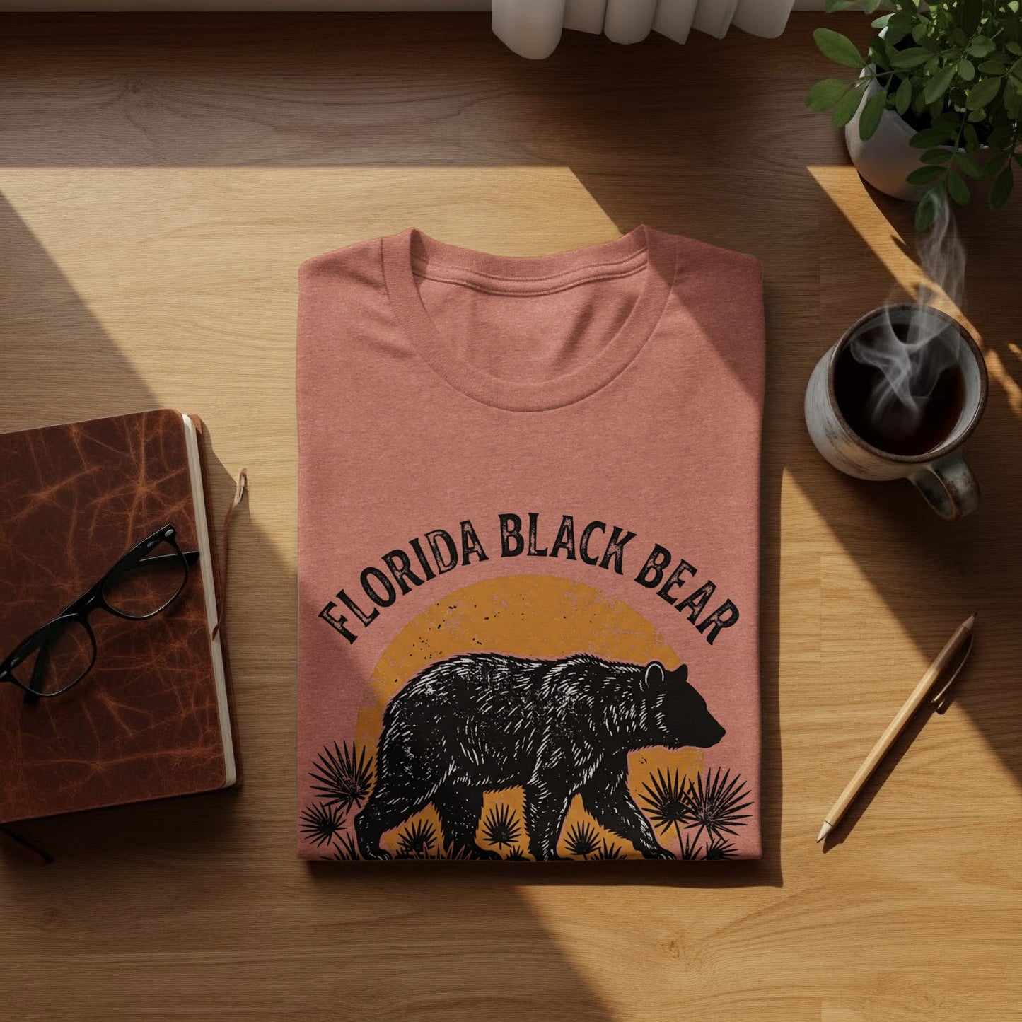 Heritage Florida Bear Trails Classic Nomad Tee: T-shirt with Florida Black Bear graphic and palm fronds, on a wooden surface.
