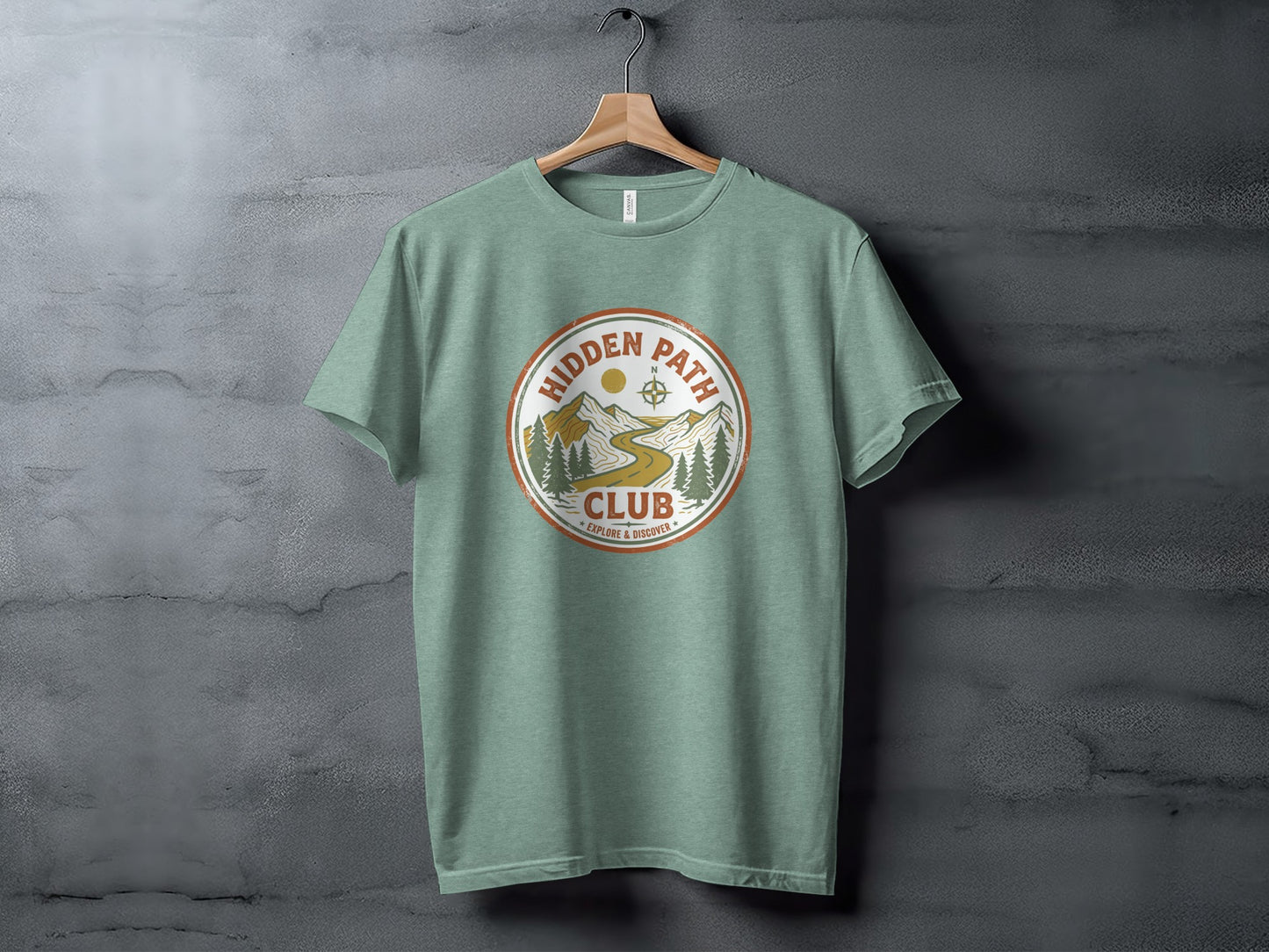 Rugged Hidden Path Club Explorer Wilderness Shirt: Green t-shirt with circular "Hidden Path Club" logo featuring mountains, trees, and a winding path.