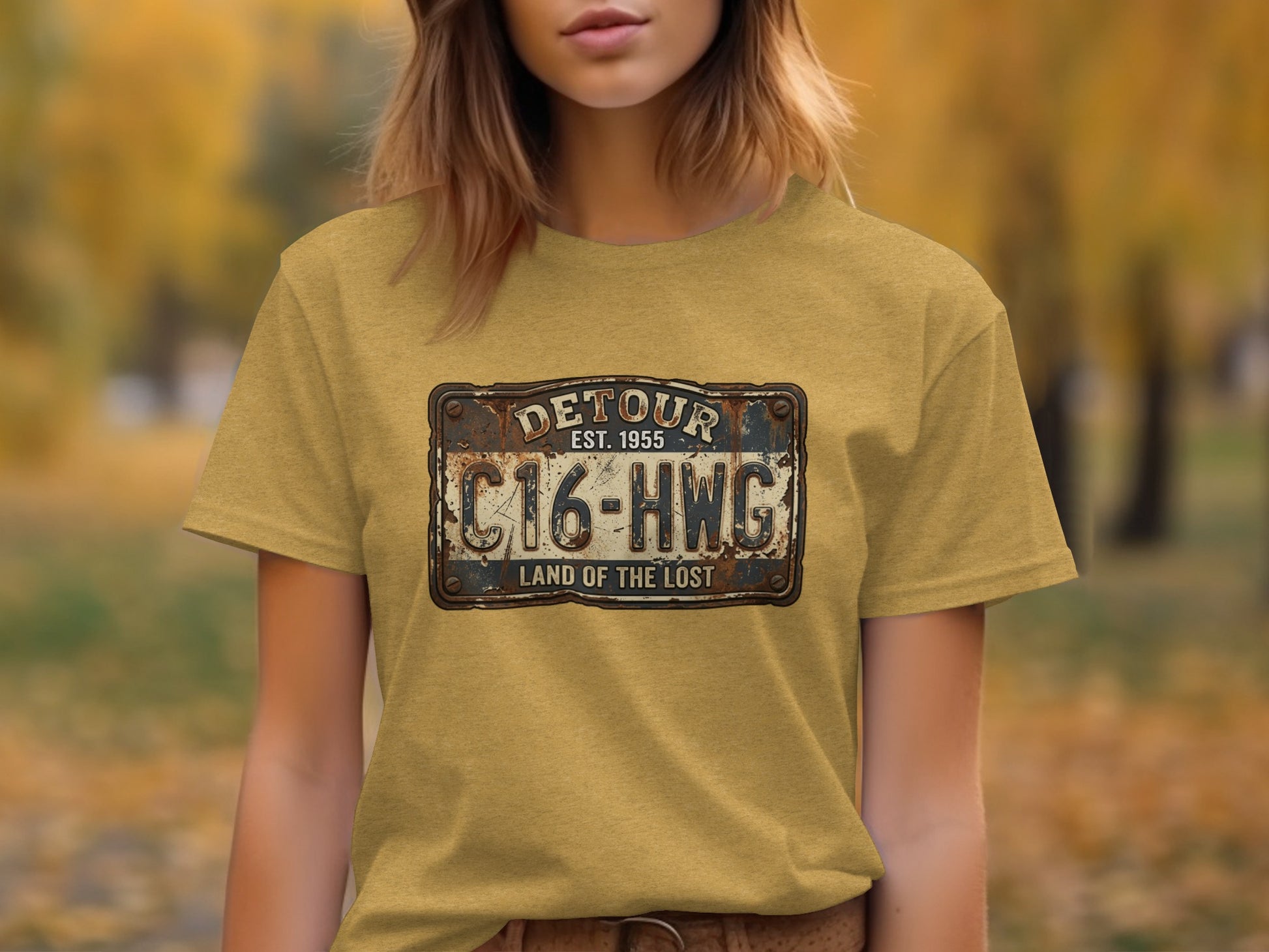 Land of the Lost Detour Plate: The Explorer's Adventure Tee: Yellow t-shirt with distressed "Detour EST 1955 C16-HWG Land of the Lost" license plate graphic.