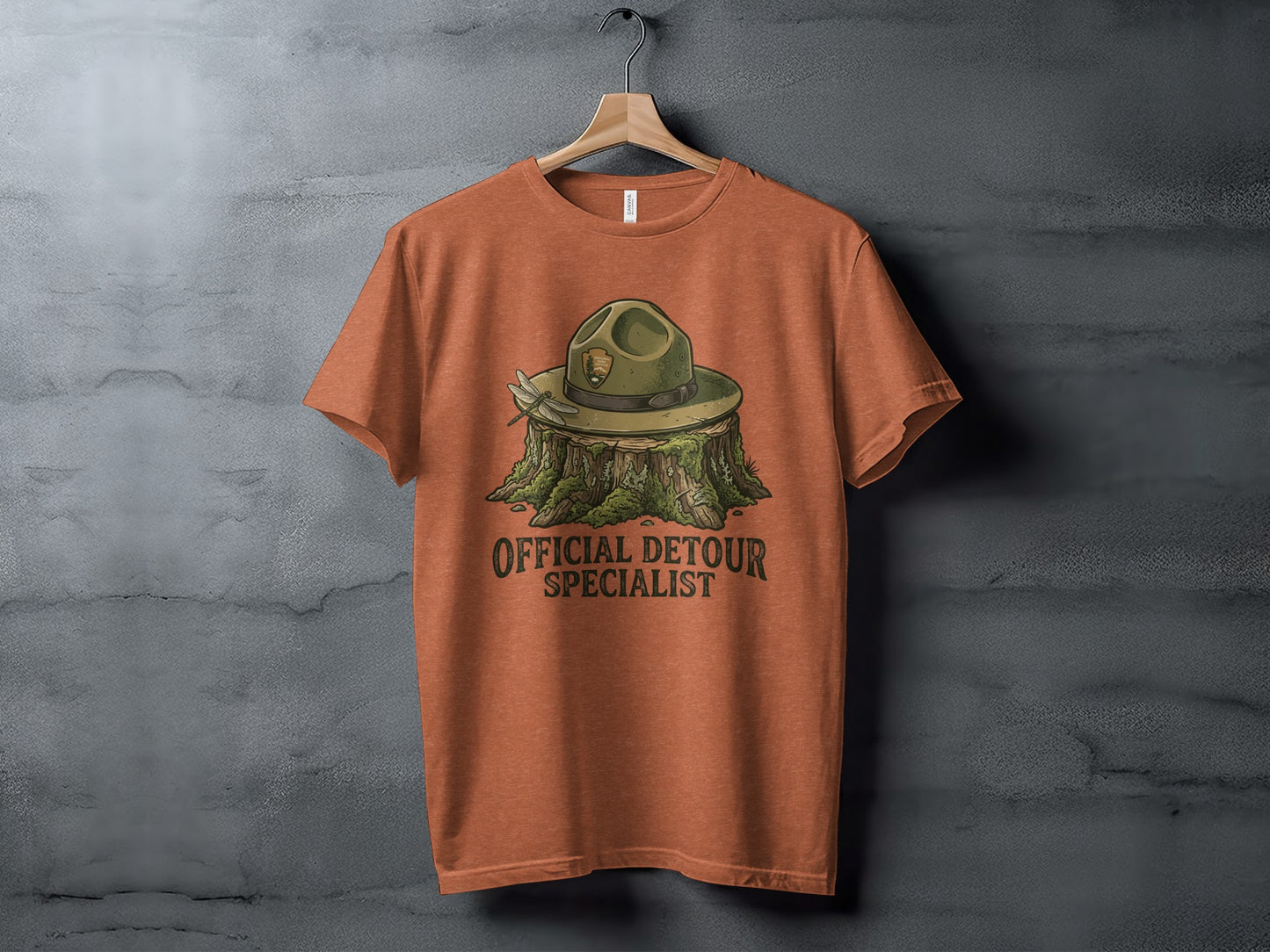 Official Detour Specialist Heritage | Vintage Outdoor Apparel: Orange t-shirt with ranger hat on a stump, "Official Detour Specialist" text.