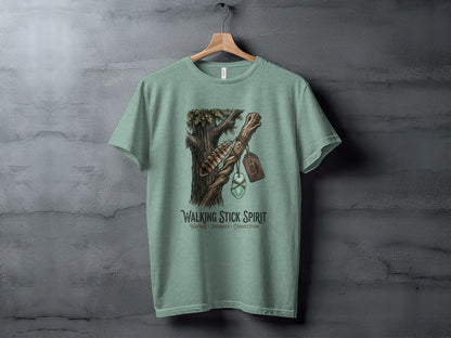 Heritage Walking Stick Spirit: Journey Nomad Tee: Green t-shirt with a nature-inspired graphic of a feather and gem on a tree branch.