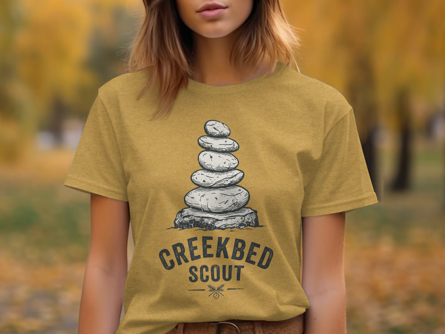 Creekbed Scout Cairn Graphic: The Explorer's Adventure Tee: Stacked stones graphic on a yellow t-shirt with "CREEKBED SCOUT" text.