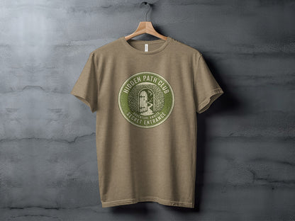 Hidden Path Club: Secret Entrance | Vintage Outdoor Apparel: Green circular logo on a taupe t-shirt reading "Hidden Path Club" and "Adventure Awaits Secret Entrance."