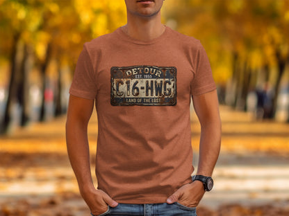 Land of the Lost Detour Plate: The Explorer's Adventure Tee: Brown t-shirt with a distressed "DETOUR" sign graphic and "C16-HWG LAND OF THE LOST".