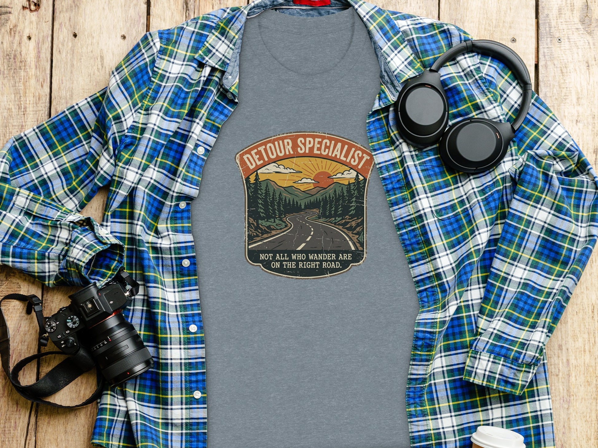Heritage Detour Specialist Vintage Graphic Nomad Tee: Gray t-shirt with "Detour Specialist" graphic and landscape design, on wooden background.