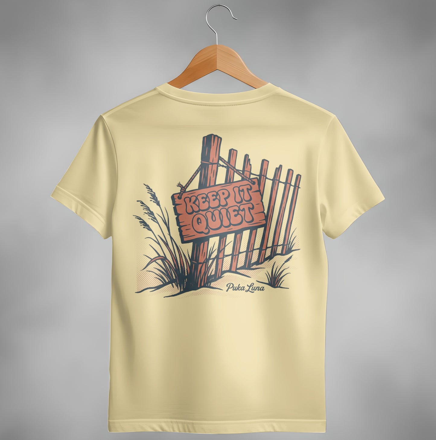 Cream t-shirt with "KEEP IT QUIET" sign on fence illustration.