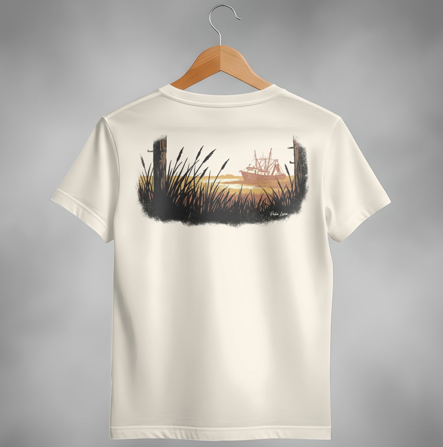 T-shirt back with a painted scene of a fishing boat at sunset behind tall grass.