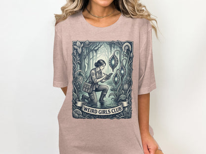 Woman in pink t-shirt with "Weird Girls Club" graphic of woman in botanical illustration.