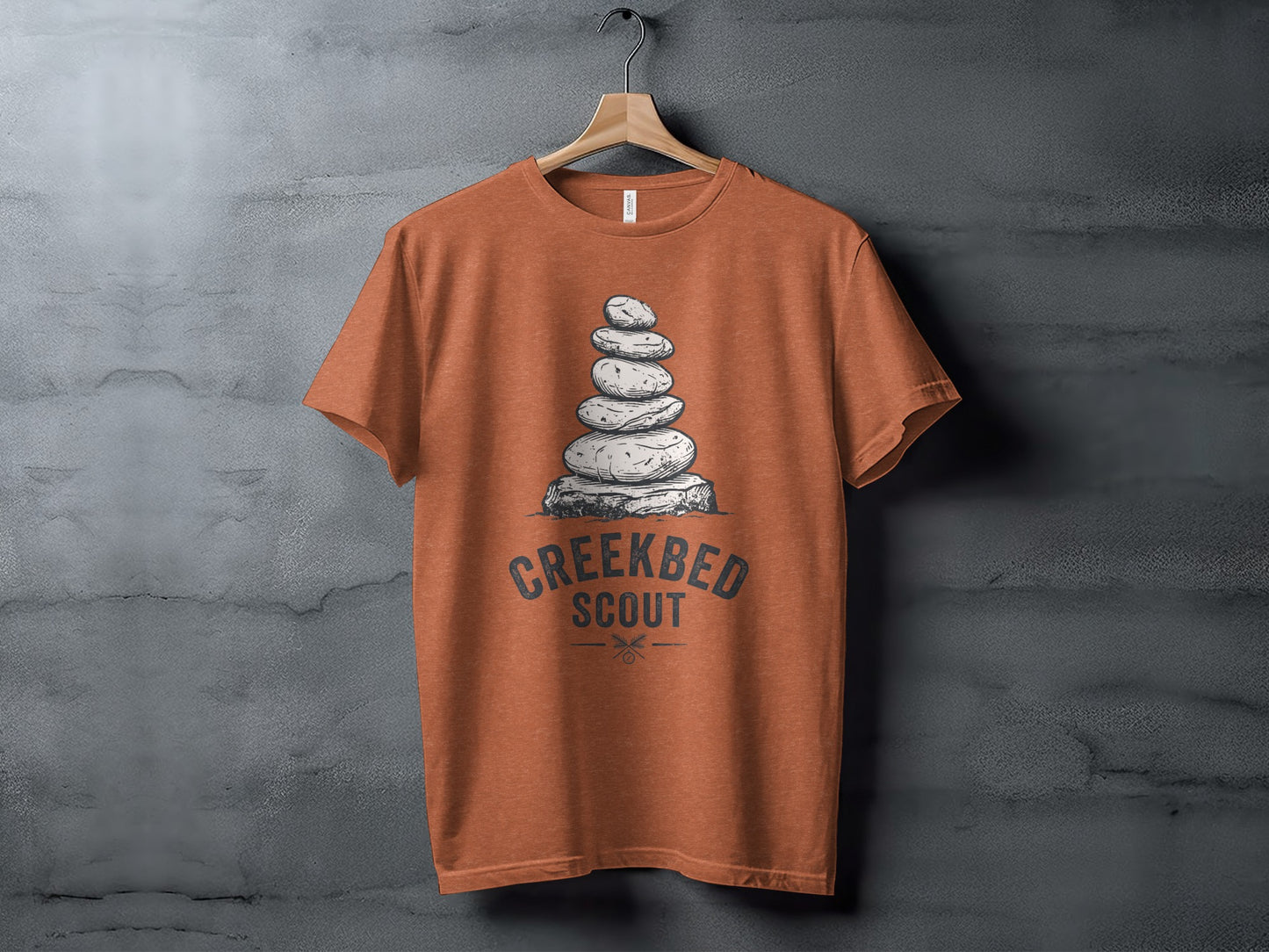 Creekbed Scout Cairn Graphic: The Explorer's Adventure Tee: Orange t-shirt with stacked stones and "Creekbed Scout" text.