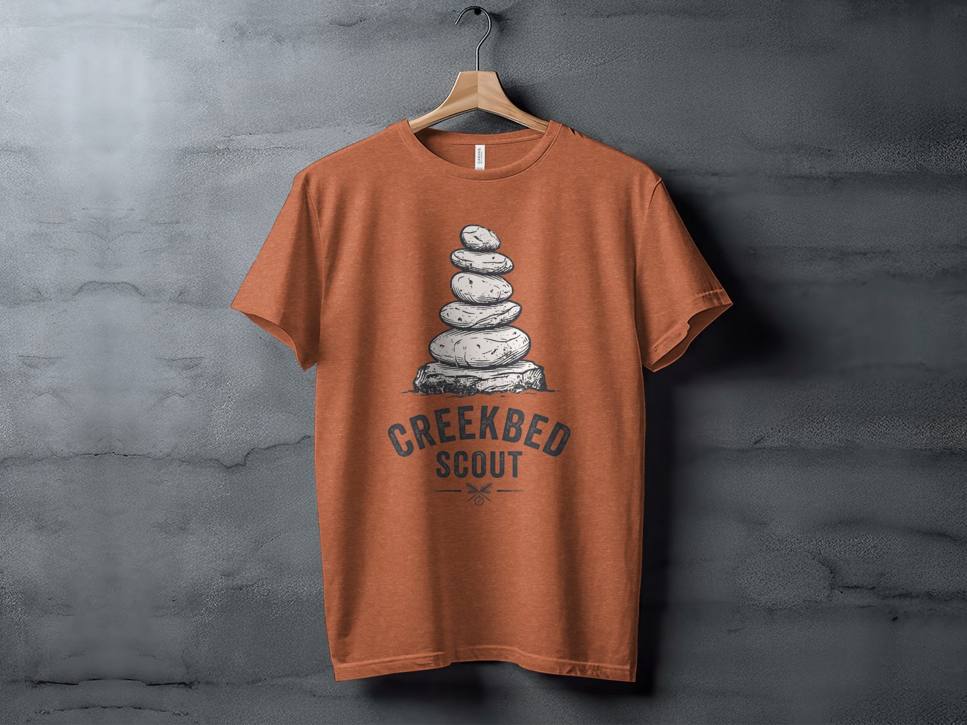 Creekbed Scout Cairn Graphic: The Explorer's Adventure Tee: Orange t-shirt with stacked stones and "Creekbed Scout" text.