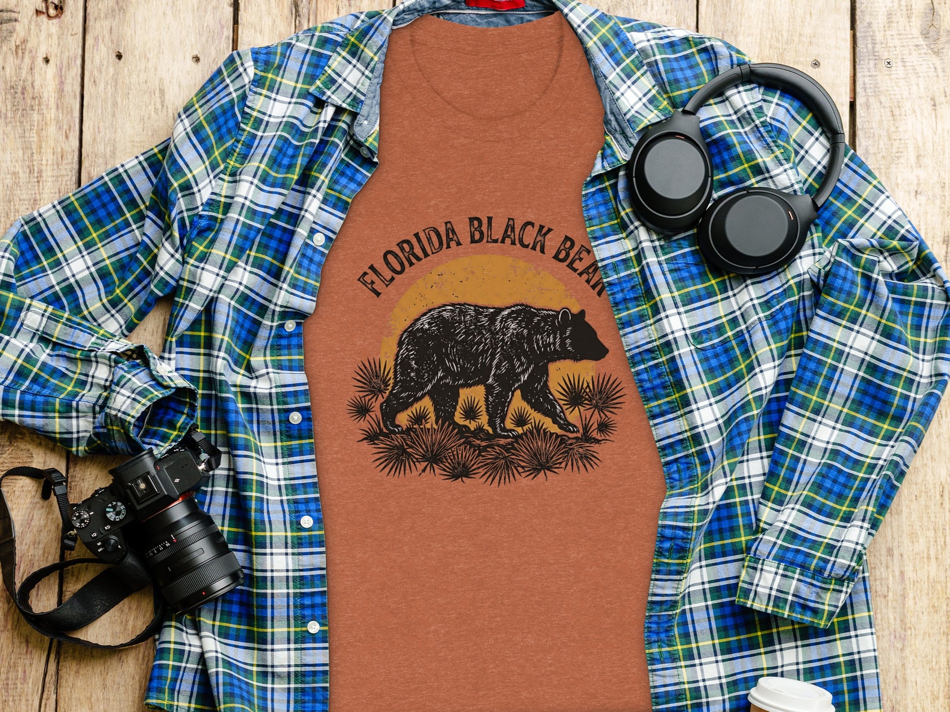 Heritage Florida Bear Trails Classic Nomad Tee: Brown t-shirt with Florida Black Bear graphic, next to a camera and headphones.