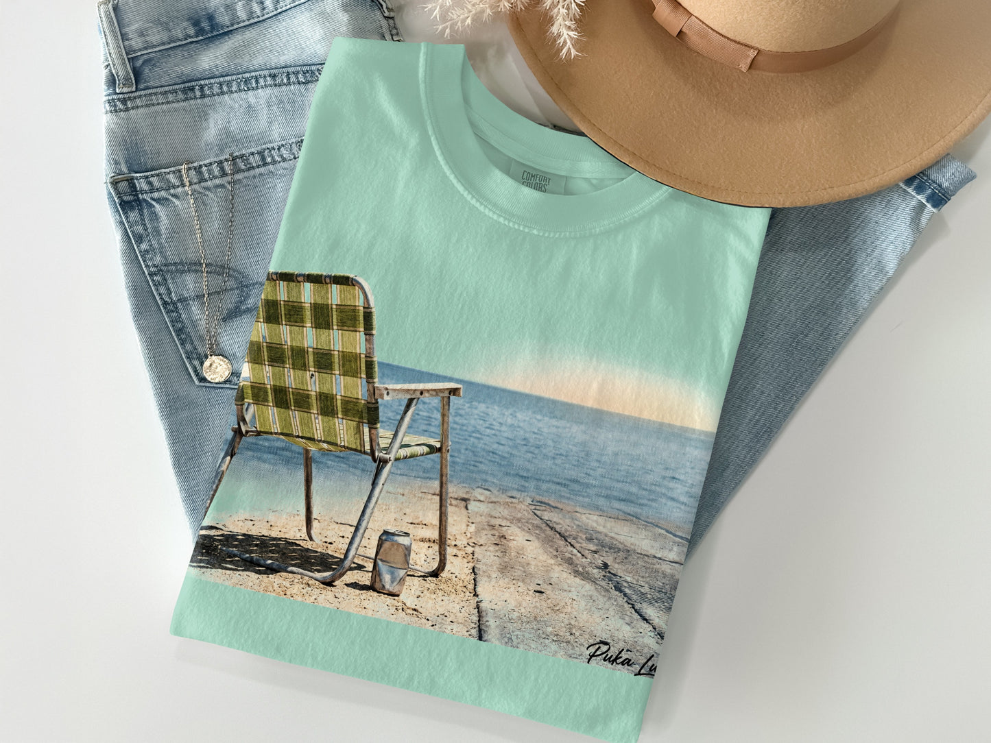 T-shirt with beach chair and ocean scene, blue jeans, and hat.
