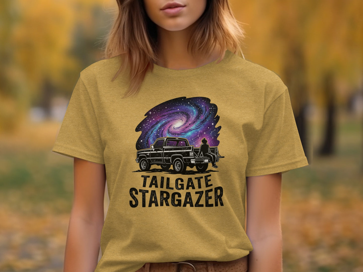 Heritage Cosmic Tailgate Stargazer Nomad Tee: Black truck under a starry galaxy on a gold t-shirt.