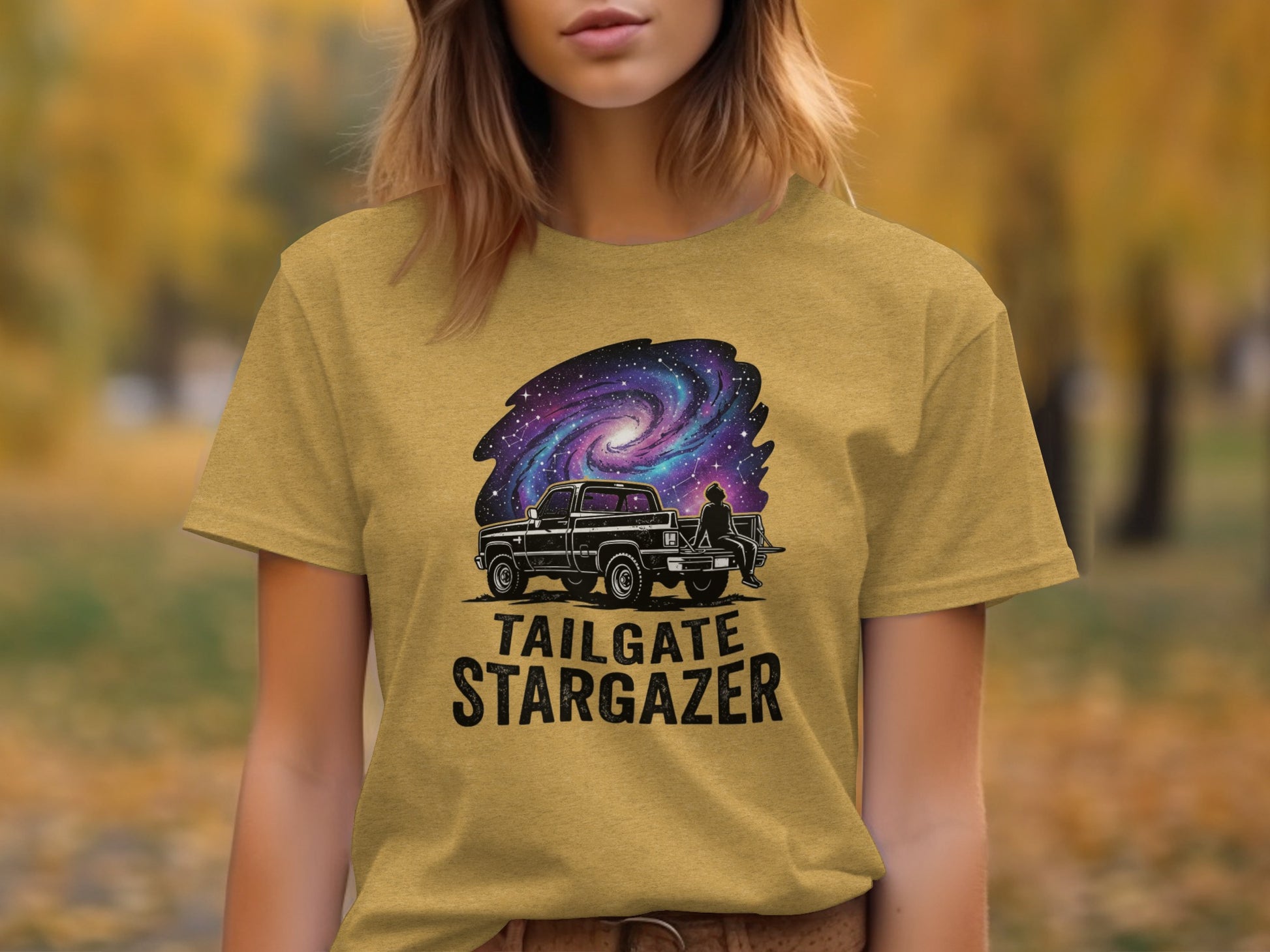 Heritage Cosmic Tailgate Stargazer Nomad Tee: Black truck under a starry galaxy on a gold t-shirt.