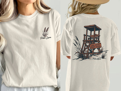 Light tan t-shirt with Puka Luna logo on front and lifeguard stand graphic on back.