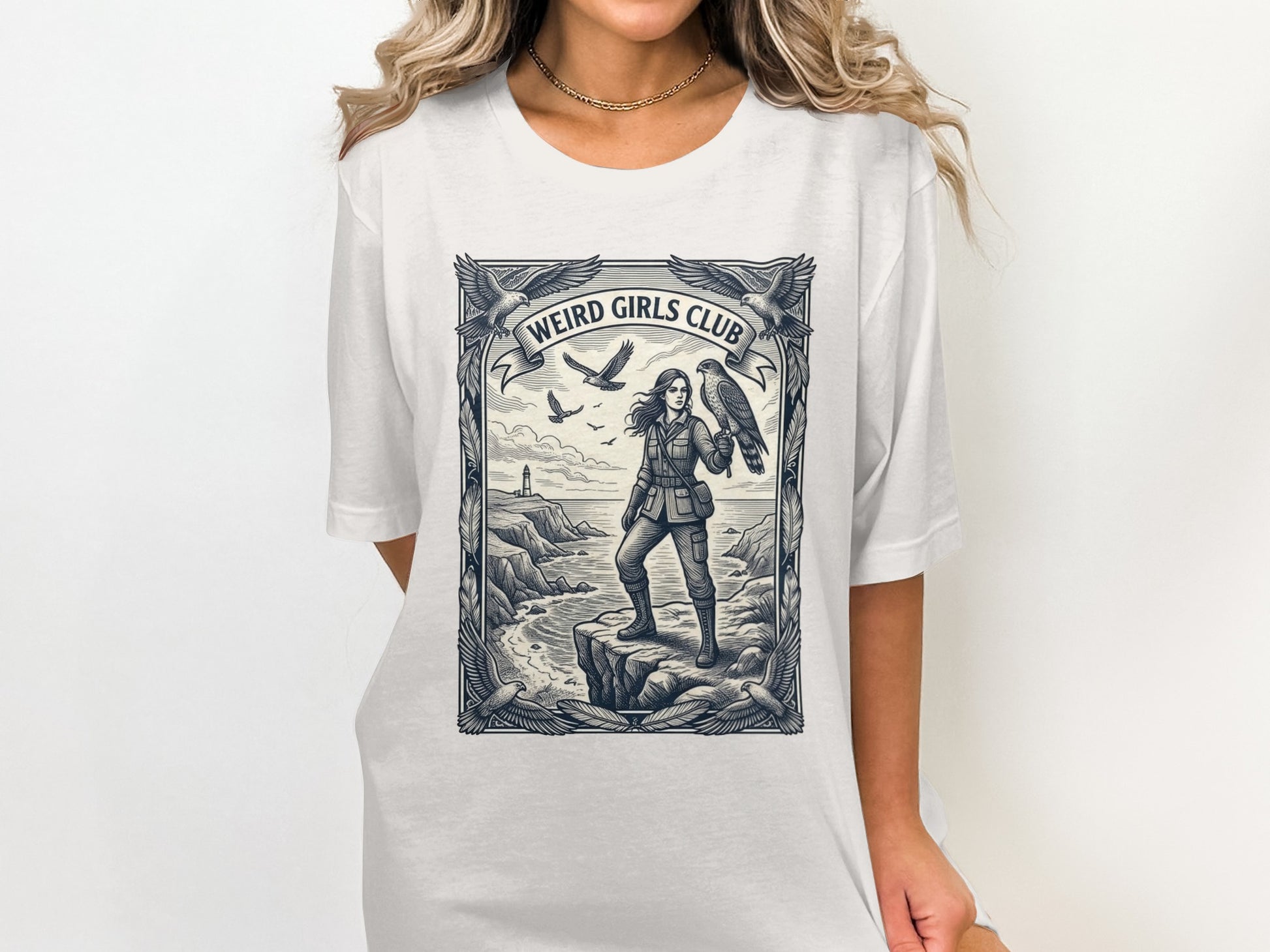 Woman in a t-shirt standing on a cliff holding a hawk.