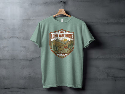 Rugged The Long Way Home | Vintage Adventure Wilderness Shirt: Green t-shirt with a shield logo featuring a scenic mountain landscape and "The Long Way Home" text.
